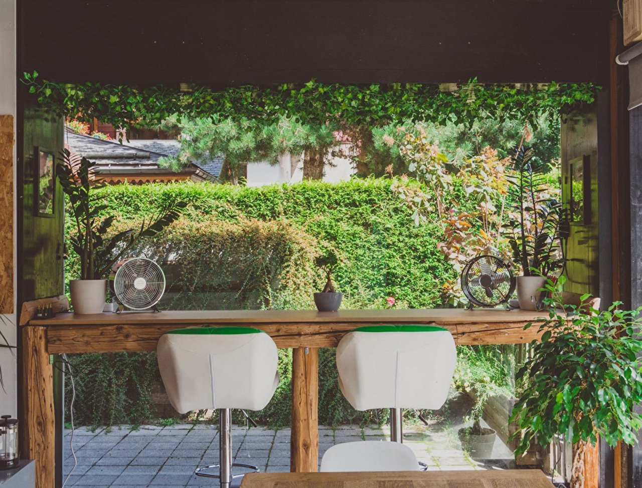Espace bureau décoré et composé d'une table haute et de fauteuils face à la végétation d'un jardin