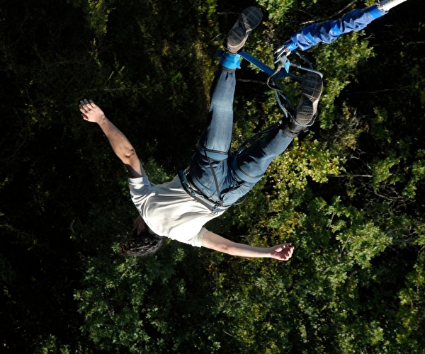 Personne effectuant un saut à l'élastique la tête en bas dans un environnement nature et vert