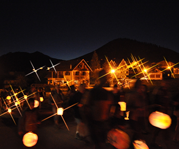 Village et habitations de nuit éclairés par des personnes tenant des lampions lumineux