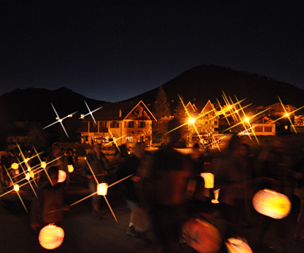 Village et habitations de nuit éclairés par des personnes tenant des lampions lumineux
