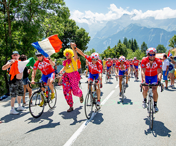 Peloton de cyclistes sur route lors du Tour de France entraîné par des personnes déguisées sur le bas côté de la route