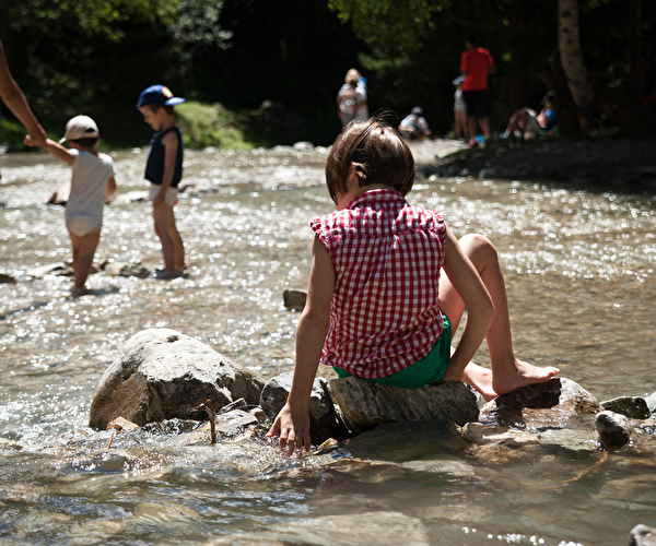 Enfants les pieds dans la rivière testant l'eau en été