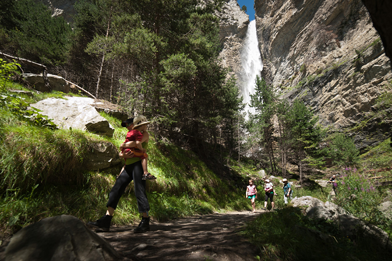 Groupe de personnes en randonnée l'été sur un chemin en forêt proche d'une cascade