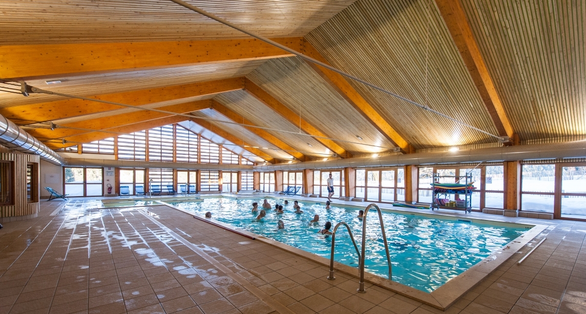 Vue sur une piscine intérieure où plusieurs personnes profitent des lieux