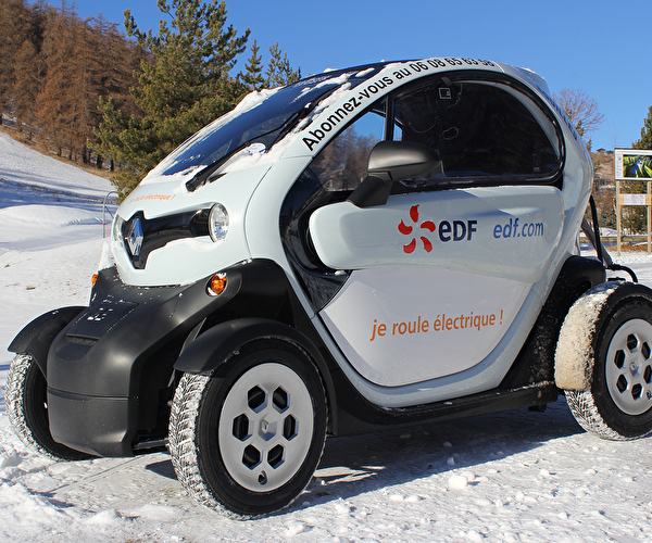 Petite voiture électrique de couleur blanche blanche garée sur la neige en montagne