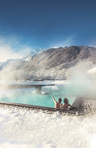 Un couple se relaxant dans un jacuzzi extérieur, avec de la neige tout autour, créant une atmosphère chaleureuse et romantique.