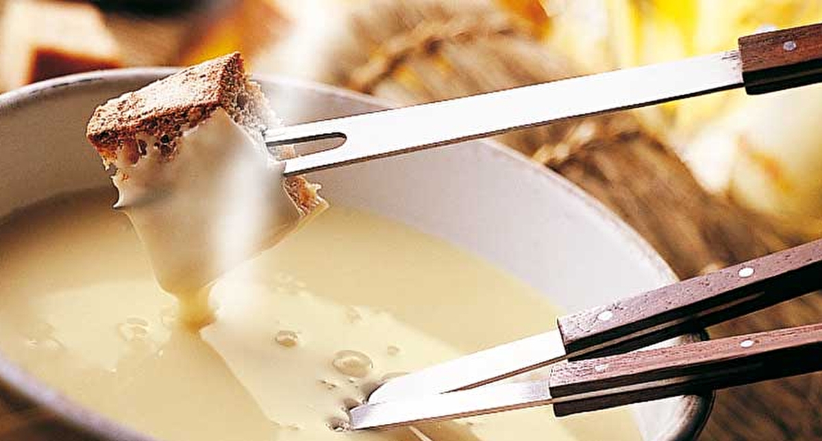 Présentation d'un plat de fondue savoyarde dans son caquelon avec des pics en bois pour tremper le pain dans le fromage