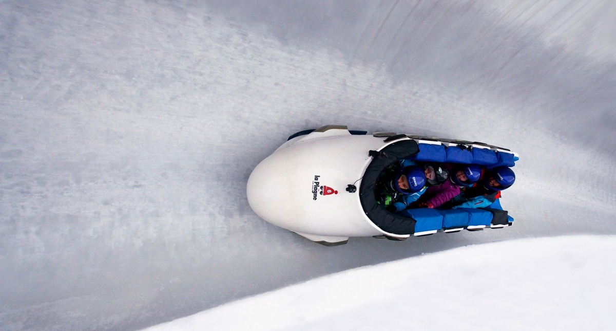 Personnes dans un bobsleigh effectuant une descente sur une piste dédiée en montagne