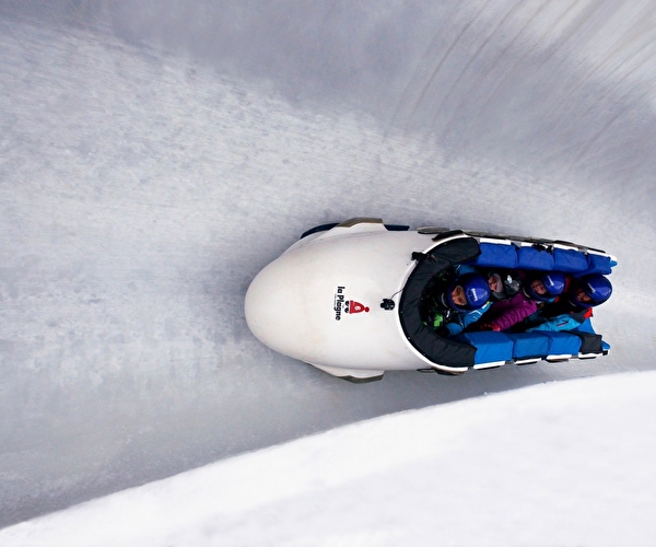 Personnes dans un bobsleigh effectuant une descente sur une piste dédiée en montagne