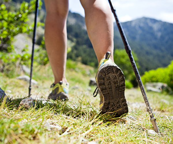 Randonneur équipé de chaussures de marche et de bâtons de marche en pleine nature lors d'une randonnée en montagne