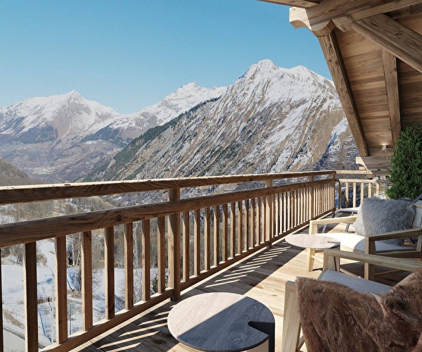 Vue sur le balcon d'un chalet en bois accueillant fauteuils et petites tables permettant d'admirer la vue sur les montagnes enneigées