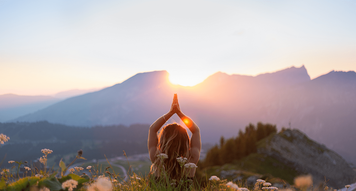 Personne face à un coucher de soleil profitant du calme pour se ressourcer en montagne
