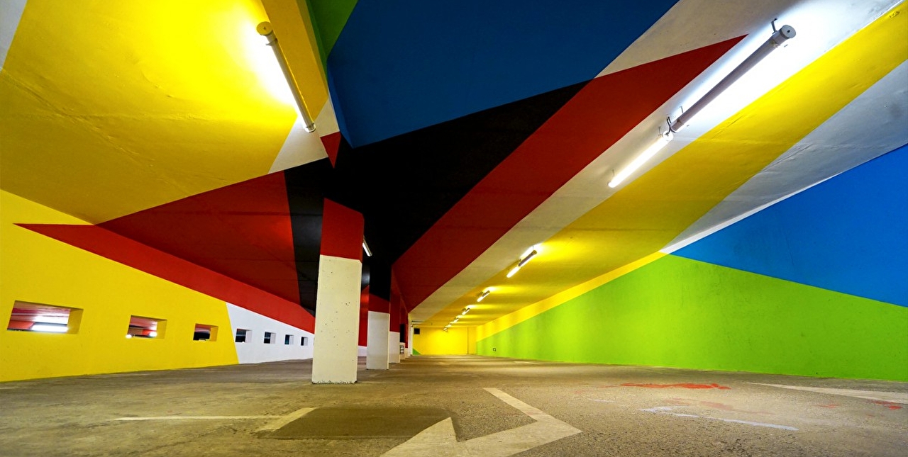 Vue sur le plafond d'un parking souterrain peint à base de couleurs vives et de formes géométriques