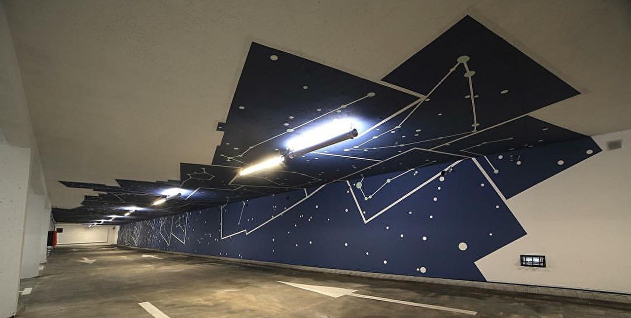 Vue sur une fresque murale représentant la voie lactée sur les murs et plafond d'un parking souterrain