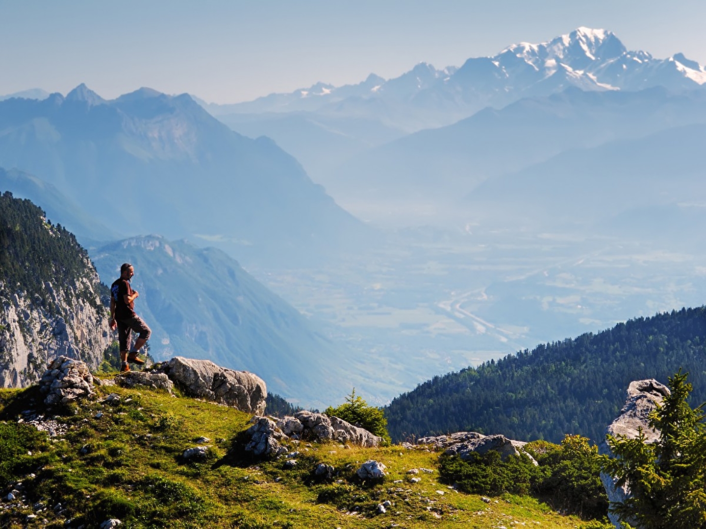 Personne en haut d'une montagne regardant les sommets enneigés et le panorama face à lui