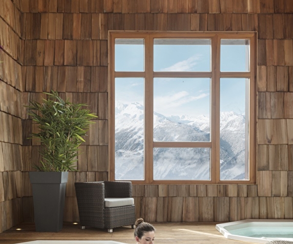 Intérieur d'un spa en bois avec plusieurs jacuzzis de relaxation face aux montagnes l'hiver