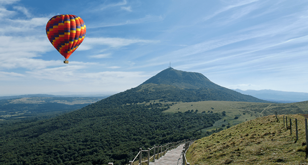 Montgolfière colorée surplombant les vallées verdoyantes et les volcans de la Chaîne des Puys