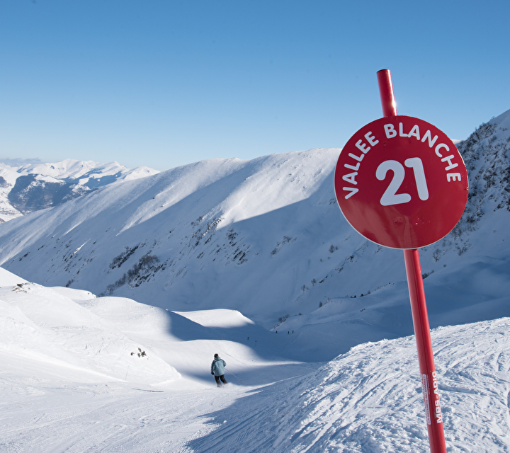 Panneau de piste rouge avec piste et skieurs en arrière plan