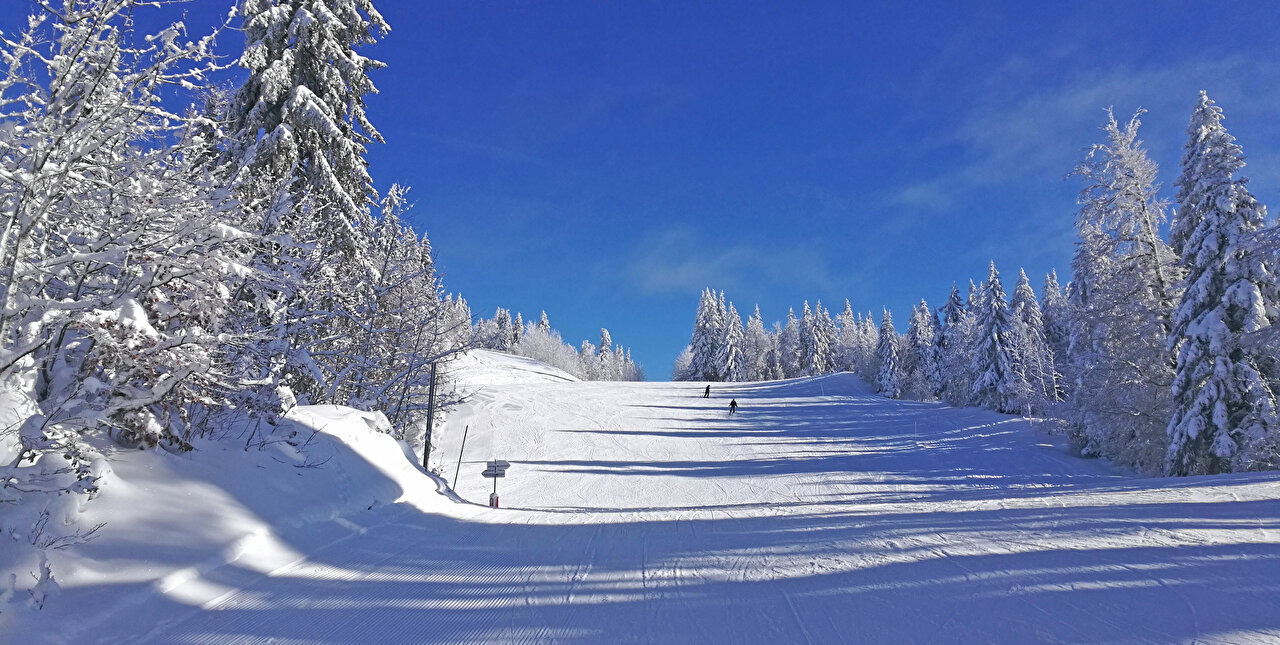 Paysage hivernal, piste de ski avec skieurs et ciel bleu