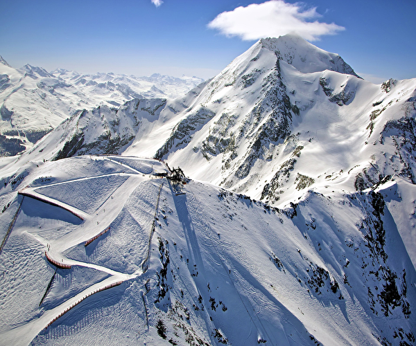 Panorama exceptionnel en montagne où se dessine une piste de ski de descente balisée en son milieu