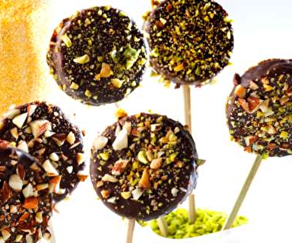 Bâtons de sucettes auréolées de macarons au chocolat tapissés d'éclats de pistaches et d'amandes