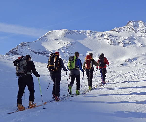 2quipée de skieurs effectuant une montée en ski de rando en file indienne en montagne l'hiver