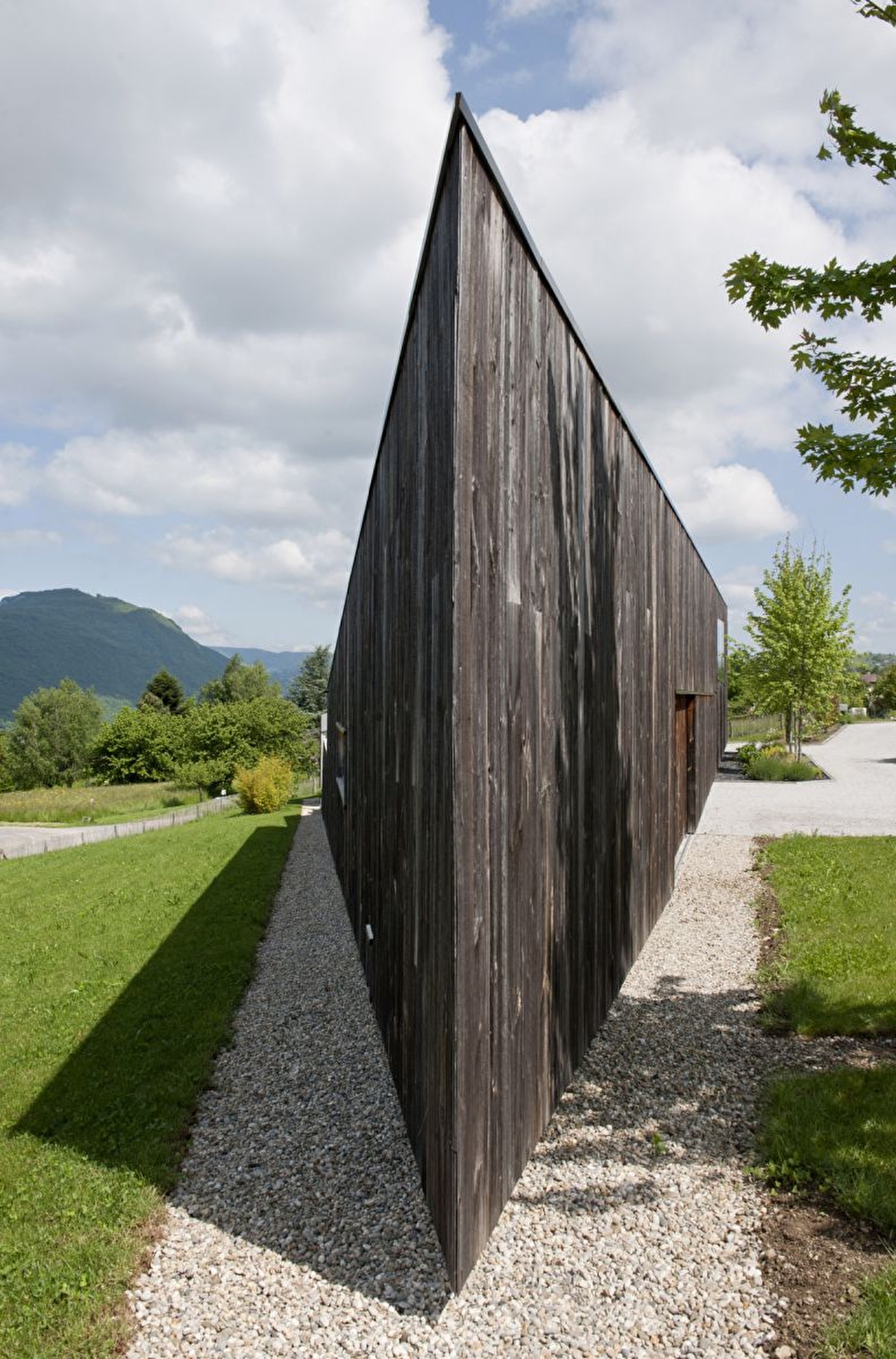 Vue sur une habitation moderne en bois de forme atypique et entourée de verdure