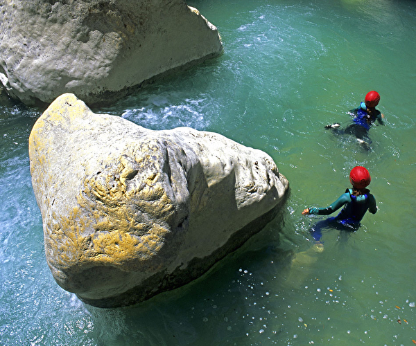 Personnes équipés de combinaisons et de casques dans l'eau lors d'une activité canyoning l'été