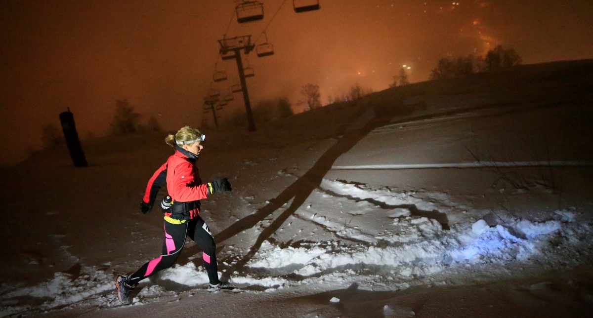 Femme effectuant une course dans la neige de nuit sous les télésièges