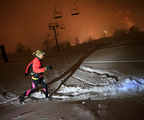Femme effectuant une course dans la neige de nuit sous les télésièges