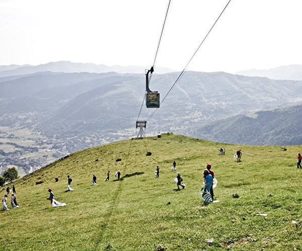 Personnes effectuant un ramassage de déchets en montagne et en pleine nature sous une rampe de télécabines