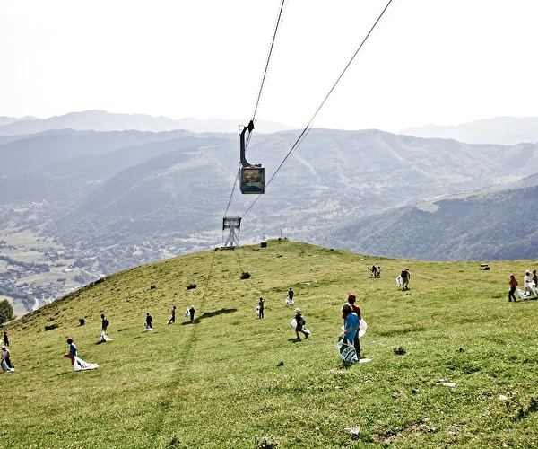 Personnes effectuant un ramassage de déchets en montagne et en pleine nature sous une rampe de télécabines