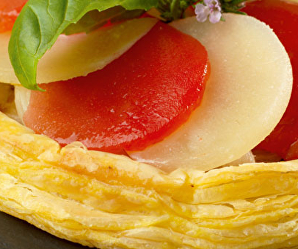 Présentation d'une tarte à base de tomates, de fromage Ossau-Iraty et de feuilles de basilic
