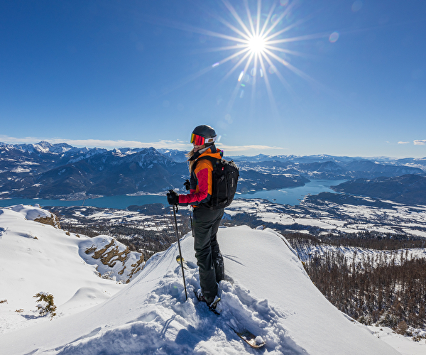 Personne sur ses skis en montagne surplombant la vallée et son panorama sous le soleil