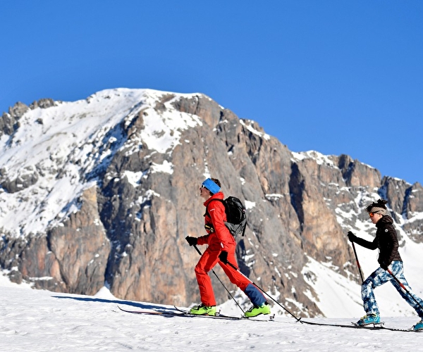 2 personnes équipés de vêtements adaptés à la montagne en randonnée à ski l'hiver
