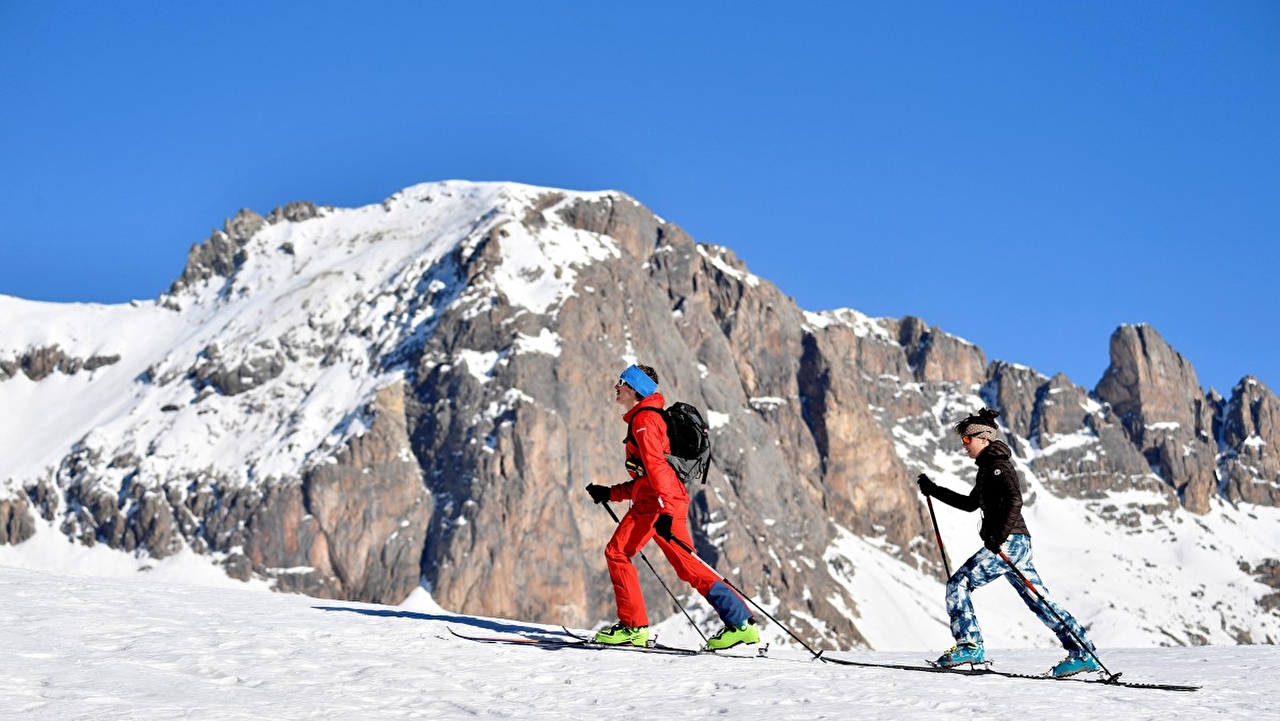 Duo de personnes effectuant une randonnée de ski à travers les montagnes enneigées