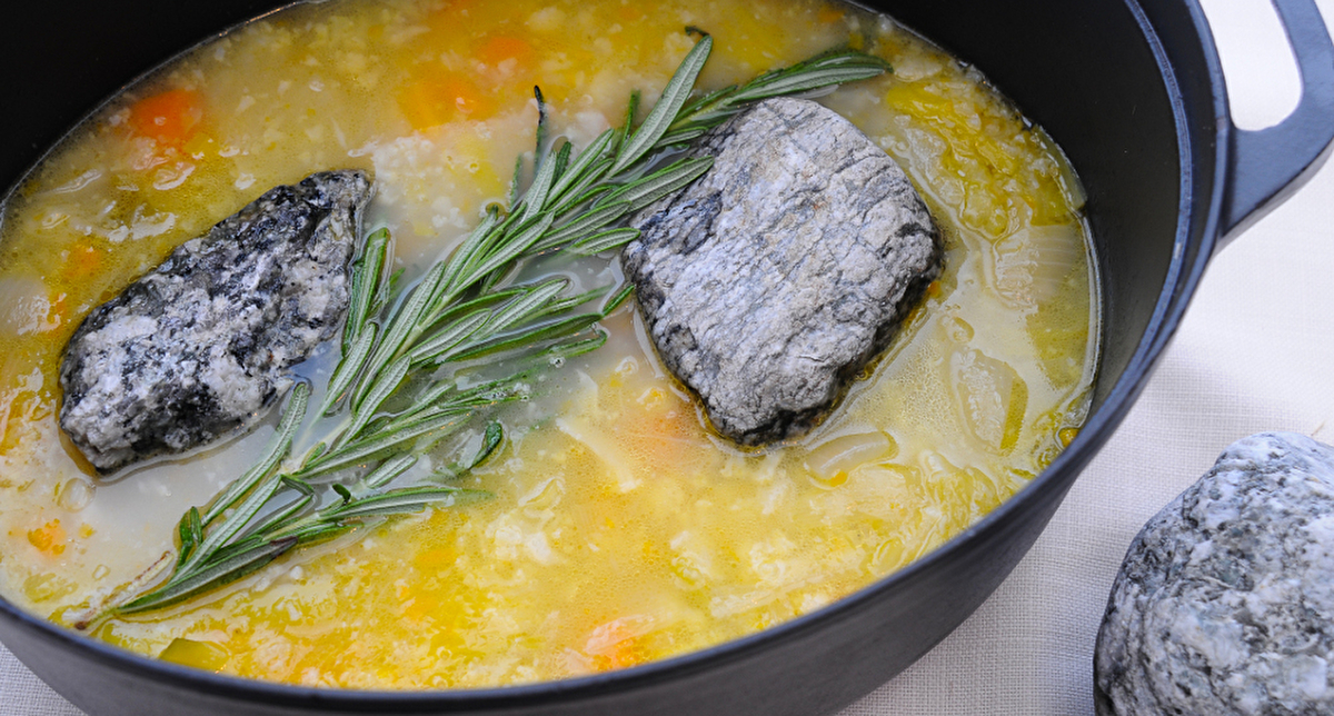 Présentation de la soupe aux cailloux dans une marmitte en fonte noire