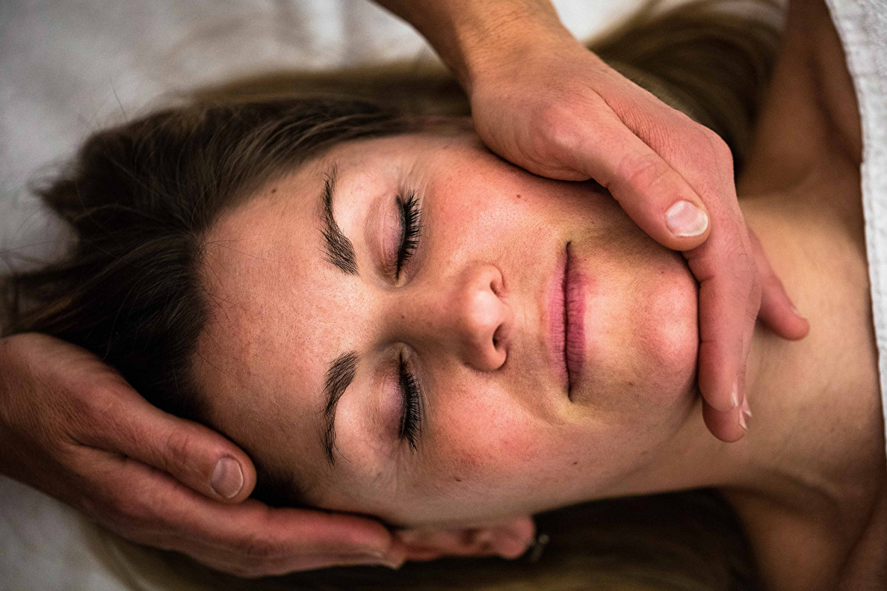 Femme en position allongée se faisant masser le visage