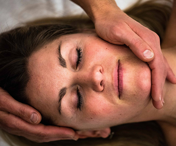 Femme en position allongée se faisant masser le visage