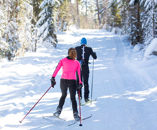 Un homme et une femme pratiquant le ski de fond dans la foret du Lac Blanc dans les Vosges