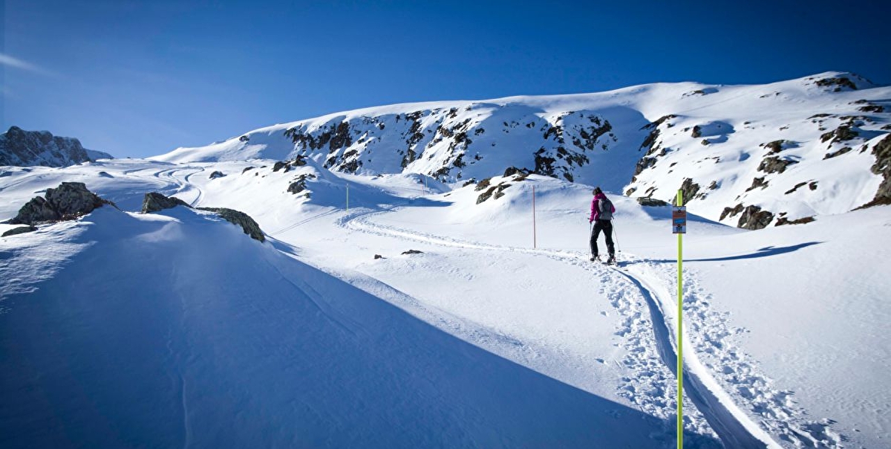 Personne effectuant une marche en montagne aidé par des piquets balises