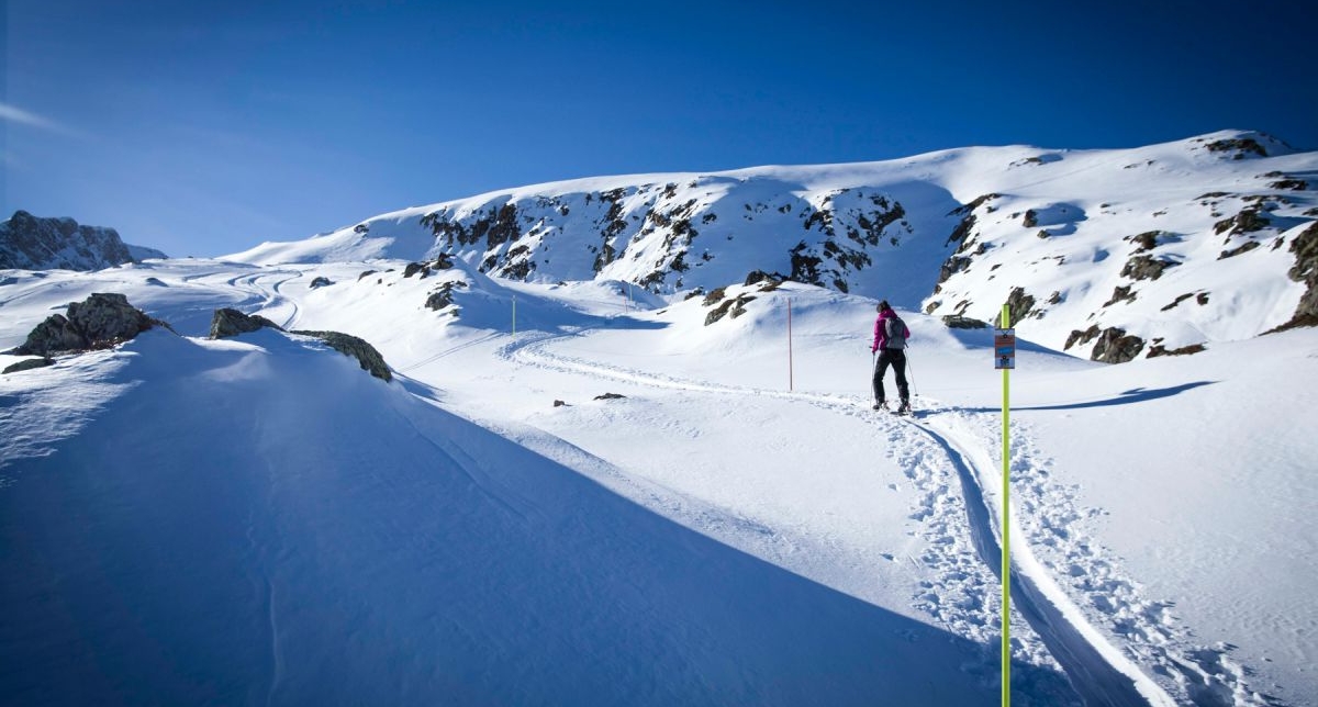 Personne effectuant une montée en ski de randonnée sur neige en pleine montagne