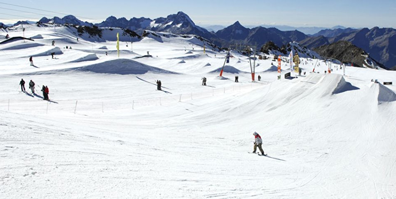 Zone de pistes en station occupée par des skieurs avec différents tremplins à disposition