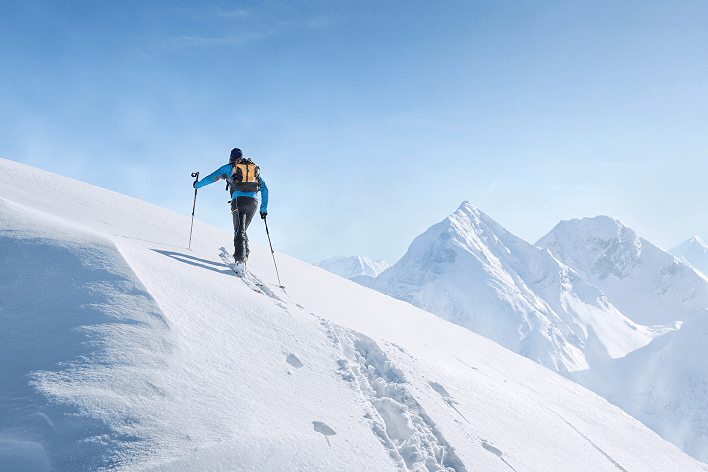 Personne effectuant une randonnée et montant une montagne avec ses équipements de ski