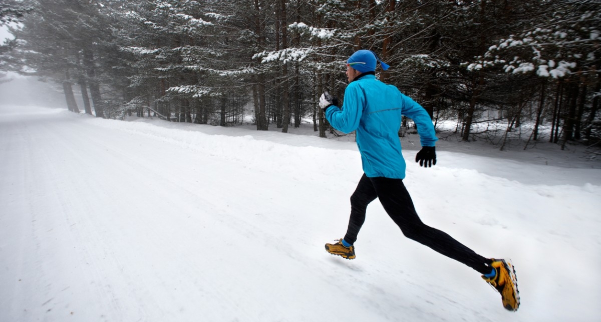 Personne en tenue de sport effectuant une course dans la neige près des sapins en montagne l'hiver