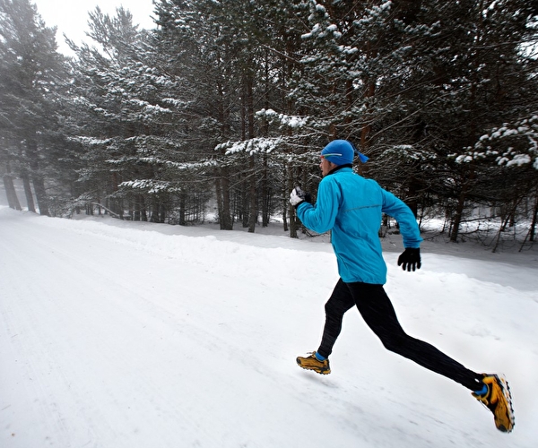 Personne en tenue de sport effectuant une course dans la neige près des sapins en montagne l'hiver