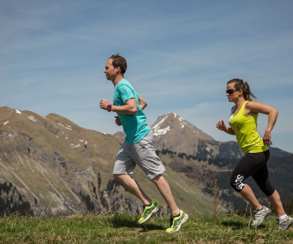 Duo de personnes effectuant une course trail en montagne l'été sous le soleil