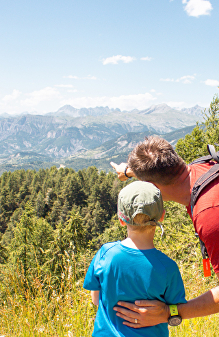 Un homme et un garçon admirent les montagnes majestueuses au loin, partageant un moment de contemplation.