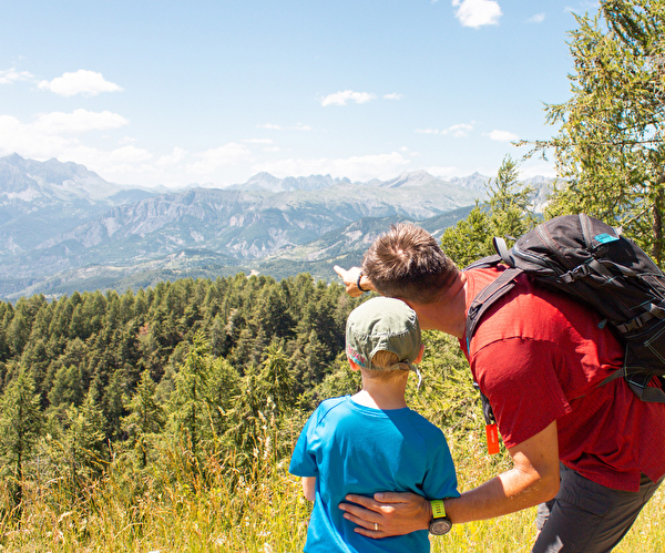 Un homme et un garçon admirent les montagnes majestueuses au loin, partageant un moment de contemplation.