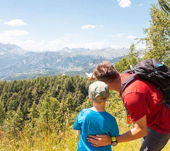 Un homme et un garçon admirent les montagnes majestueuses au loin, partageant un moment de contemplation.